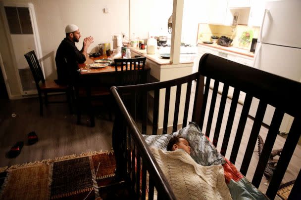 PHOTO: Najib Mohammadi sits at the dining table while his son Yasar Mohammadi, 1, sleeps in a cot in the living room of their apartment in Sacramento, Calif., March 27, 2022. (Brittany Hosea-Small/Reuters)