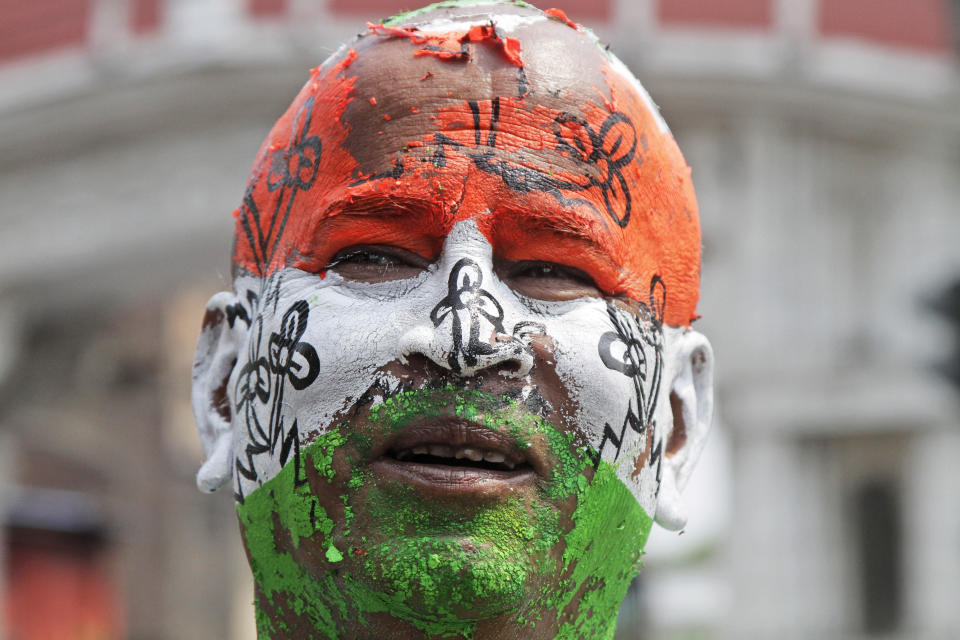 A Trinamool Congress party supporter stands with his face painted in the colors of the party flag, on a road leading to the residence of Chief Minister Mamata Banerjee in Kolkata, India, Thursday, May 23, 2019. Indian Prime Minister Narendra Modi's party claimed it had won reelection with a commanding lead in Thursday's vote count, while the stock market soared in anticipation of another five-year term for the pro-business Hindu nationalist leader. (AP Photo/Bikas Das)