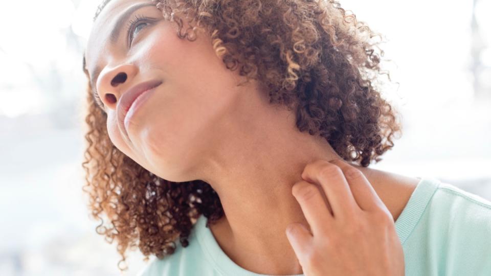 A woman scratching her neck while tilting her head to the side