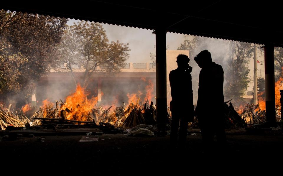 People are silhouetted against multiple burning funeral pyres of patients who died of the Covid-19 coronavirus disease at a crematorium on April 24, 2021 in New Delhi, India - Anindito Mukherjee/Getty Images