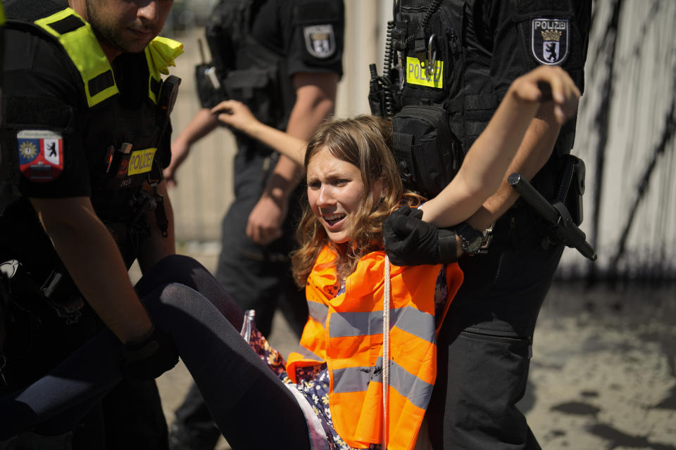 Police officers carry away climate activist Lina Schinkoethe during a protest with the group Uprising of the Last Generation at the chancellery in Berlin, Germany, Wednesday, June 22, 2022. The group claims the world has only a few years left to turn the wheel around and avoid catastrophic levels of global warming. (AP Photo/Markus Schreiber)