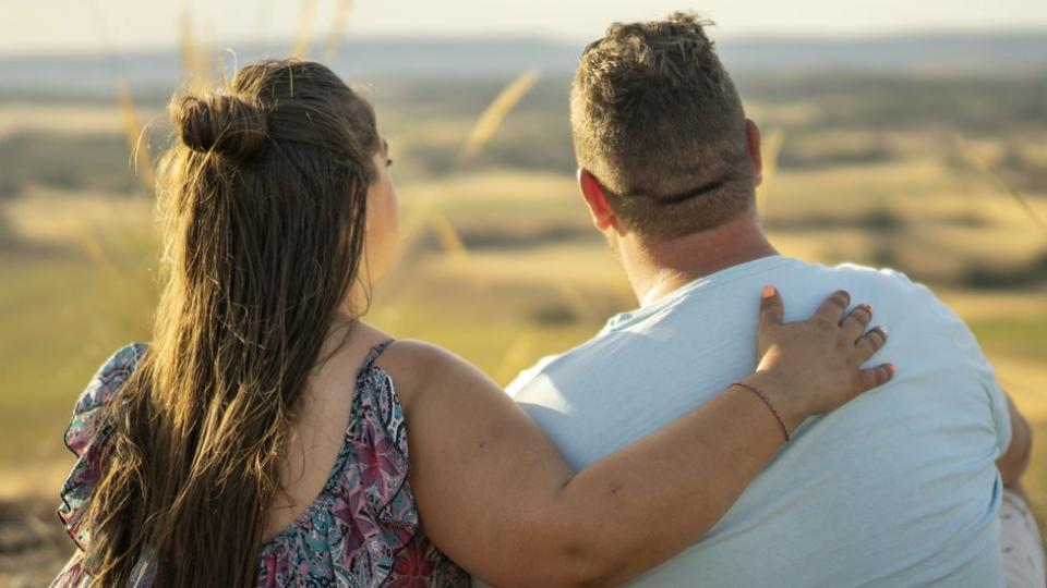 Pareja de espaldas viendo el atardecer.