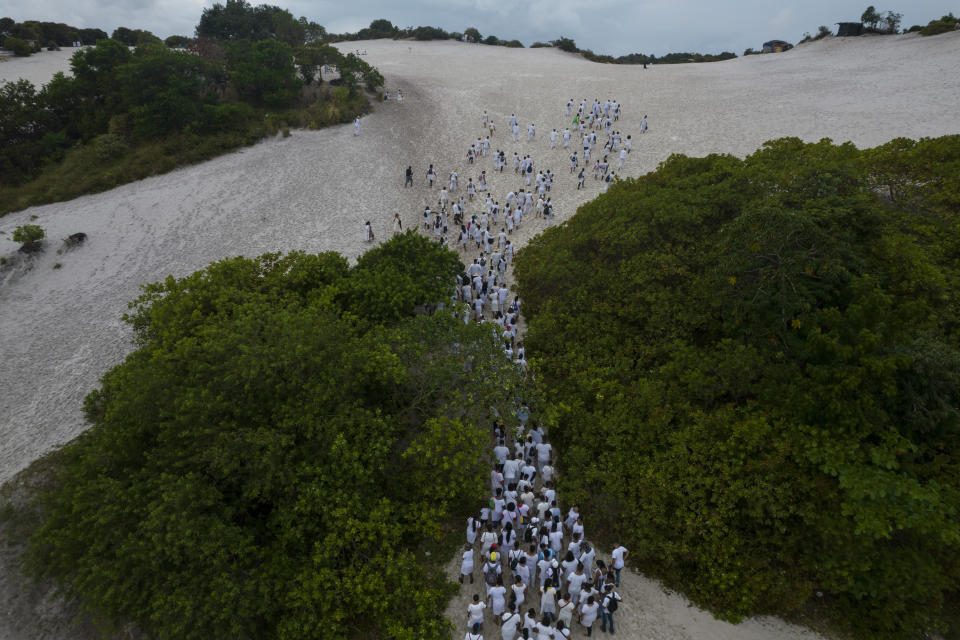 Medaberel Baptist Church members walk to the top of an area in the Abaete dune system, to arrive at a steep rise of sand they call the "Holy Mountain", in Salvador, Brazil, Sunday, Sept. 18, 2022. This year the dunes have become a flashpoint after City Hall began building a plaza and welcome center at one spot along their base. Defenders of the project say it's necessary to protect the fragile dunes from the increasingly heavy foot traffic (AP Photo/Rodrigo Abd)