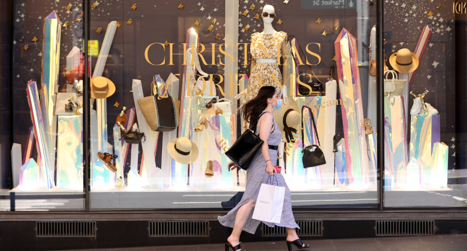 A woman with shopping bags in front of a Christmas window display.