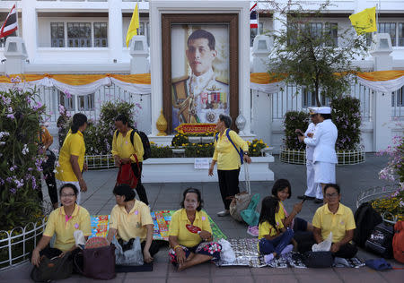 People sit near an image of King Maha Vajiralongkorn during his coronation in Bangkok, Thailand, May 4, 2019. REUTERS/Athit Perawongmetha