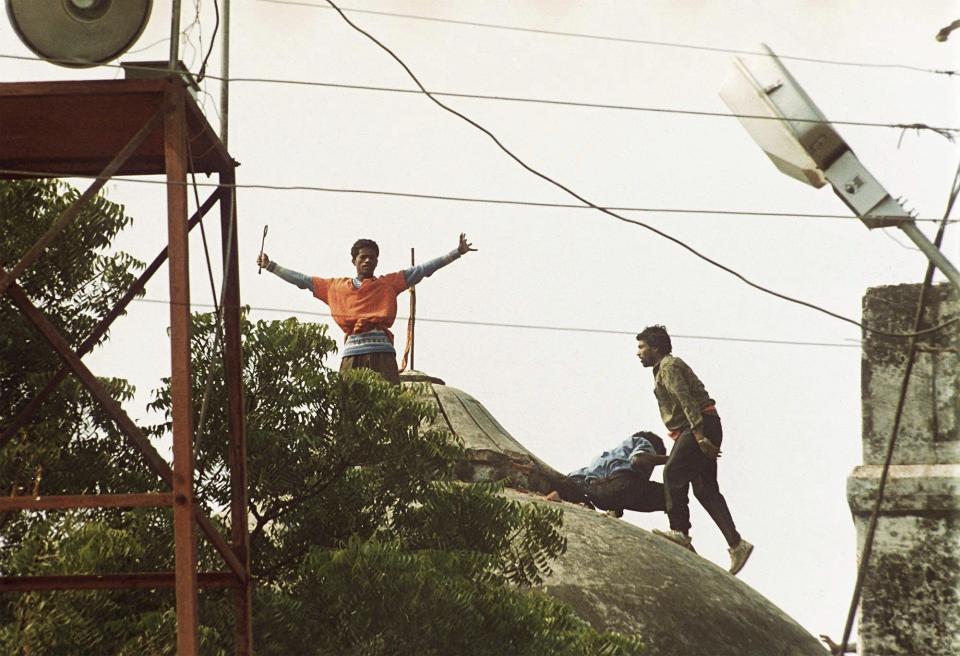 FILE - Hindu hard-liners stand on top of one of the three domes of the 16th century Babri mosque before it was destroyed in Ayodhya, India, Dec. 6, 1992. Three decades after Hindu mobs tore down the historical mosque, Indian Prime Minister Narendra Modi will attend the consecration of a grand Hindu temple at the same site on Monday in a political move to boost his party ahead of a crucial national vote. (AP Photo/Udo Weitz, File)