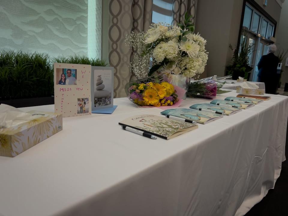 Guest books, flowers and cards are placed on a table at the public funeral service for the six victims of the mass killing in Ottawa.