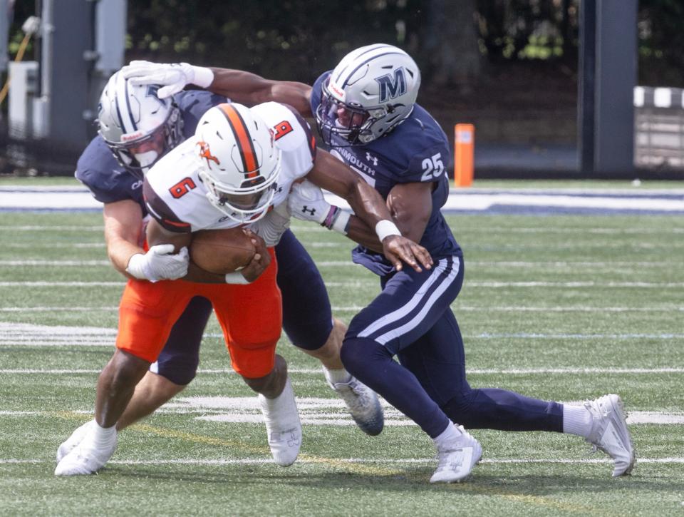 Campbell quarterback Hajj-Malik Williams is tackled by Monmouth's Ryan Moran (left) and Jude Umunakwe during a game on Sept. 16, 2023 in West Long Branch, N.J.