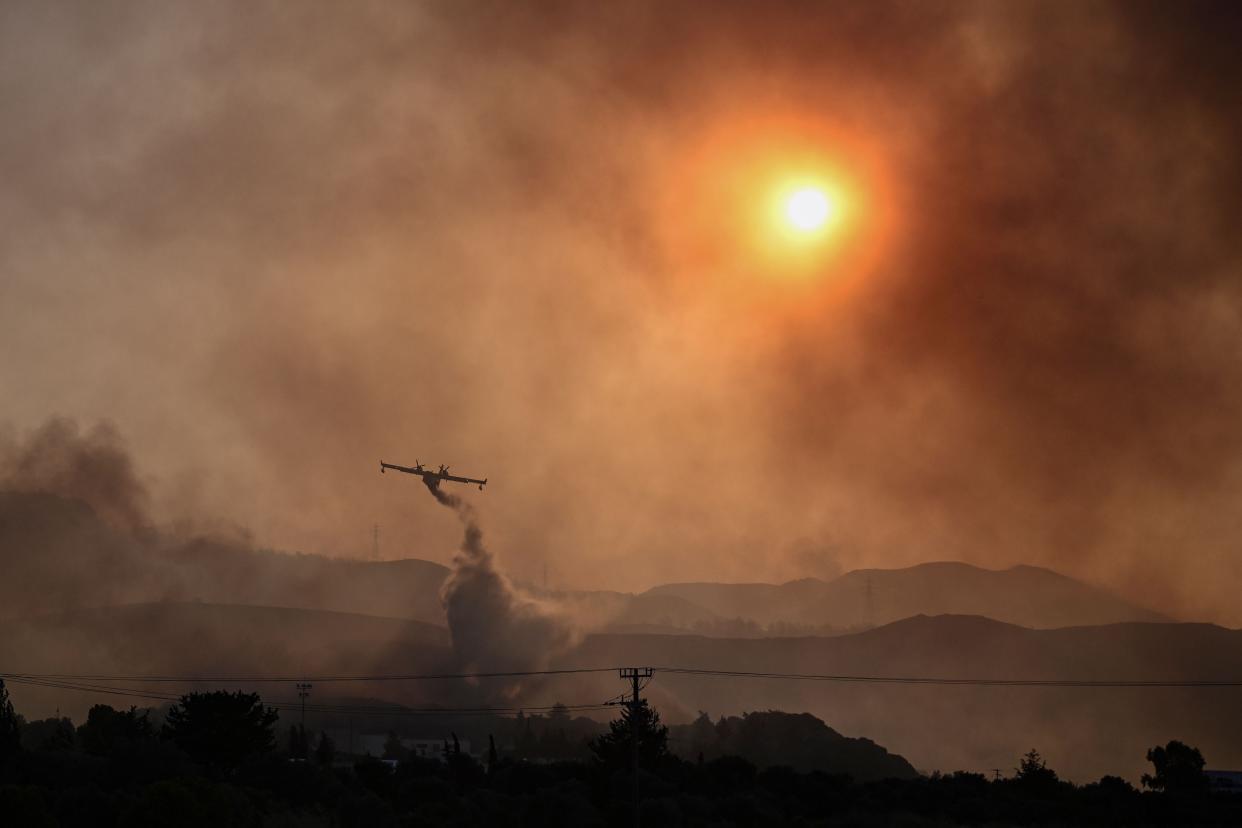 A Canadair firefighting airplane sprays water on a fire in the southern part of the Greek island of Rhodes (AFP via Getty Images)