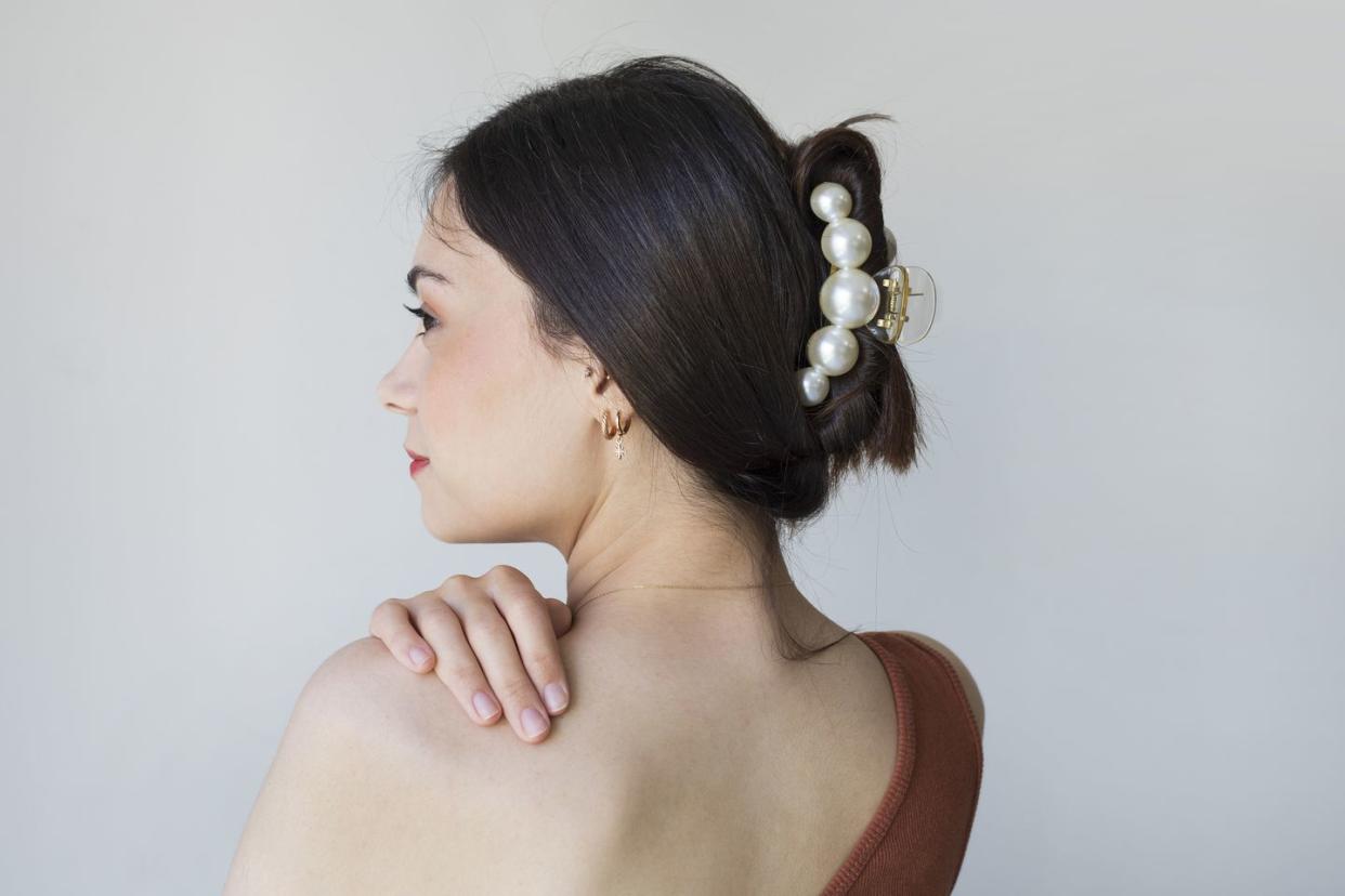 young woman with beautiful hair clip on grey background