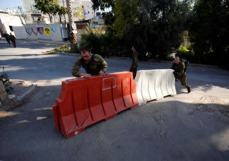 Israeli soldiers push barries at a military camp in the West Bank city of Hebron October 17, 2017. REUTERS/Mussa Qawasma