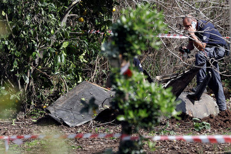 An Israeli security personnel member speaks on his phone next to fragments of a Syrian anti-aircraft missile found in Alonei Abba about 2 miles (3.2 km) from where the remains of a crashed F-16 Israeli war plane were found in the village of Alonei Abba, Israel February 10, 2018. REUTERS/ Ronen Zvulun