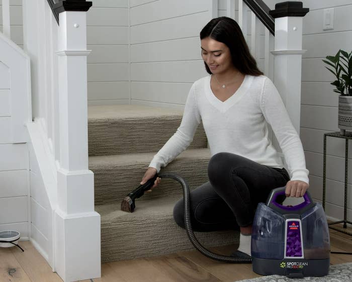 a person cleaning a carpeted stair with the cleaner