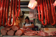 FILE - In this May 15, 2020 file photo, a butcher wears a mask as she works inside a public market in the Xochimilco district of Mexico City. Fear of hospitals, deep-rooted distrust of authorities, difficulties accessing medical care, and the pressure to make a living amid economic uncertainty are fueling the spread of COVID-19 in this southern borough of the capital. (AP Photo/Rebecca Blackwell, File)