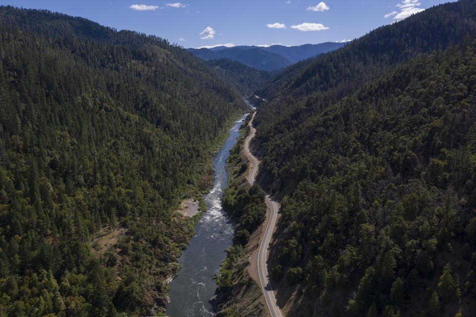The Klamath River winds runs along Highway 96 on Monday, June 7, 2021, near Happy Camp, Calif. Competition over the water from the river has always been intense, but this summer there is not enough for all users. Native American tribes along the 257-mile-long river are watching fish species they have fished for generations hover closer to extinction as water flow are reduced. (AP Photo/Nathan Howard)