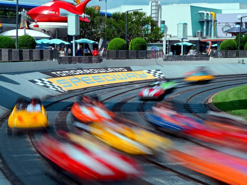 Cars speed around a race track at Walt Disney World's Tomorrowland Speedway.