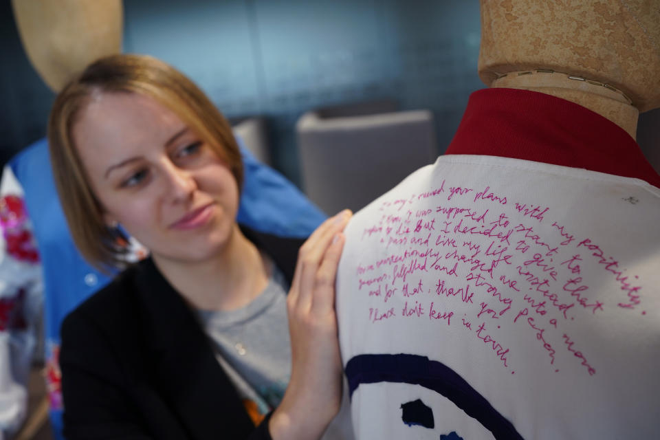 Cancer patient Laura Nuttall looks at her quote, which has been hand-stitched onto the back of one of the lab coats which has been made into a 