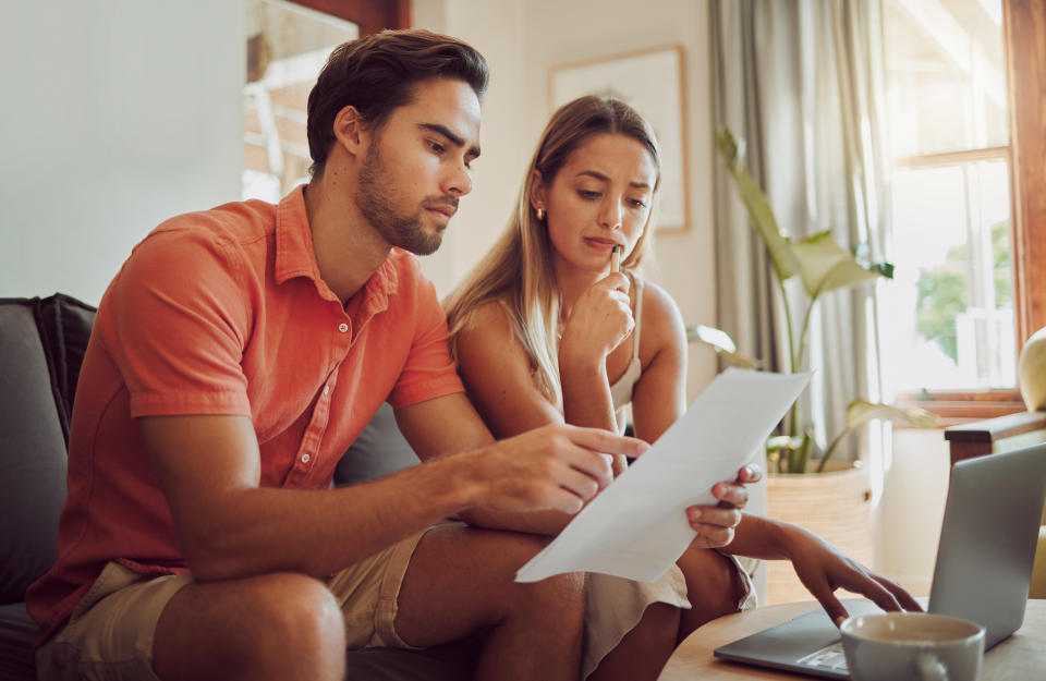 Anxiety, debt and stress with a couple paying bills on a laptop, checking their budget and savings. Young husband and wife looking worried while reading a loan application or contract together