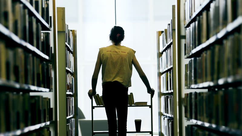 An employee at the Main Library in Salt Lake City pushes a cart between shelves of books on Sept. 21, 2020.