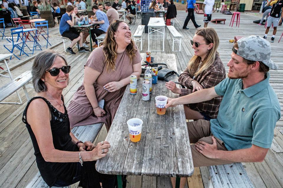 Patrons enjoy beer and drinks during happy hour on a warm day at Constitution Yards Beer Garden in Wilmington, Wednesday, April 12, 2023. In addition to beer, visitors can enjoy food and games, such as axe throwing and cornhole, and, at times, listen to live music. 