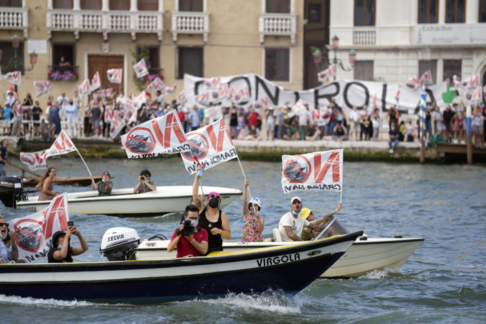 "No Big Ships" activists stage a protest as the MSC Orchestra cruise ship leaves Venice, Italy, Saturday, June 5, 2021. The 92,409-ton, 16-deck MSC Orchestra cruise ship, the first cruise ship leaving Venice since the pandemic is set to depart Saturday amid protests by activists demanding that the enormous ships be permanently rerouted out the fragile lagoon, especially Giudecca Canal through the city's historic center, due to environmental and safety risks. The ship passed two groups of protesters: pro-cruise advocates whose jobs depend on the industry as well as protesters who have been campaigning for years to get cruise ships out of the lagoon. (AP Photo/Antonio Calanni)