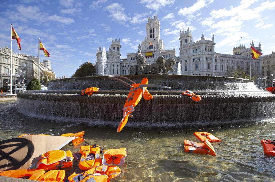 Lifejackets are thrown into the Cibeles fountain during a protest performance in Madrid, Spain, Tuesday, Dec. 3, 2019. Some 20 activists from the international group called Extinction Rebellion cut off traffic in central Madrid and staged a brief theatrical performance to protest the climate crisis. The activists held up a banner in Russian that read "Climate Crisis. To speak the truth. To take action immediately." Some 10 others dressed in red robes and with their faces whitened to symbolize the human species' peril danced briefly before police moved in to end the protest. (AP Photo/Paul White)