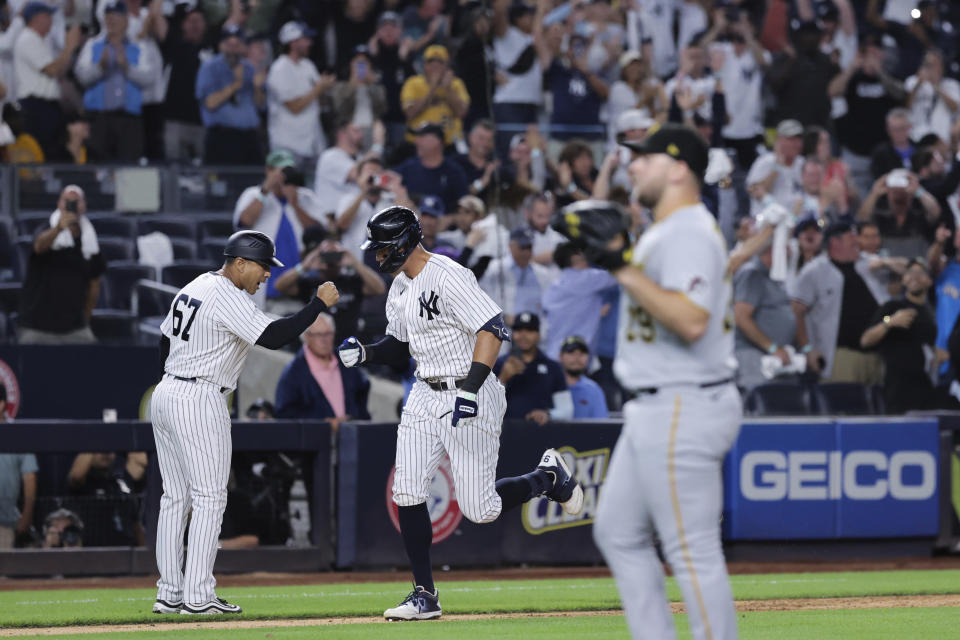 New York Yankees' Aaron Judge celebrates with third base coach Luis Rojas (67) after hitting his 60th home run of the season, as Pittsburgh Pirates relief pitcher Wil Crowe waits during the ninth inning of a baseball game Tuesday, Sept. 20, 2022, in New York. (AP Photo/Jessie Alcheh)