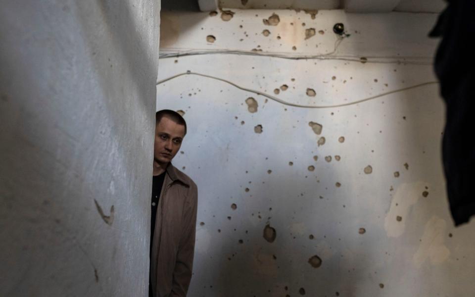 A man stands inside a building in front of a wall damaged from shrapnel following a Russian attack on the previous night, in the residential area of Mikolaiv, Ukraine, on Tuesday, March 29, 2022. - AP Photo/Petros Giannakouris