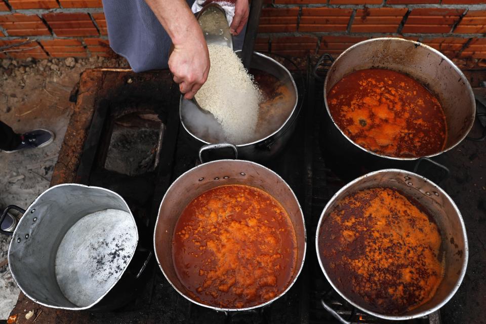 Chef Walter Ferreira pours rice into a stew at a soup kitchen in Luque, Paraguay, Monday, May 11, 2020. The number of soup kitchens in the country has increased, as the country's economy grinds down due to the new coronavirus pandemic lockdown. (AP Photo/Jorge Saenz)