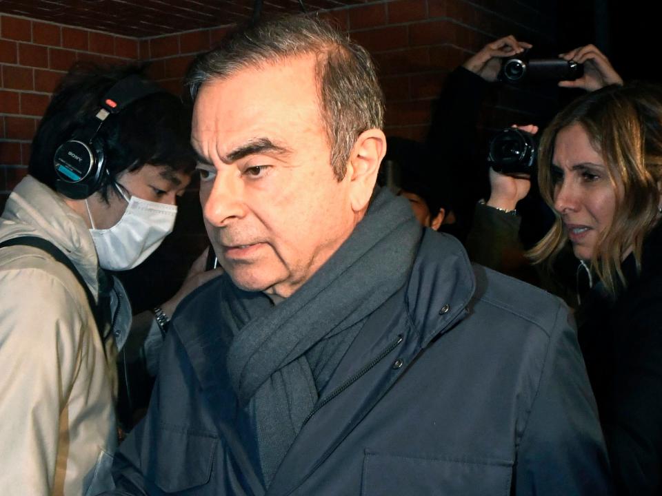 FILE - In this April 3, 2019, file photo, former Nissan Chairman Carlos Ghosn, center, returns to his residence in Tokyo.  Japanese court approves release for detained Nissan ex-chair Ghosn on 500 million yen, or $4.5 million, bail.(Kyodo News via AP)