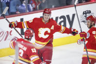 Calgary Flames' Matthew Tkachuk, center, celebrates his goal against the Winnipeg Jets with Johnny Gaudreau, left, and Elias Lindholm during the first period of an NHL hockey game Saturday, Nov. 27, 2021, in Calgary, Alberta. (Larry MacDougal/The Canadian Press via AP)