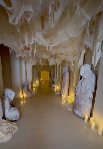 Kim Kardashian shares shot of spooky hallway decorated with candles and white cloaked statues.