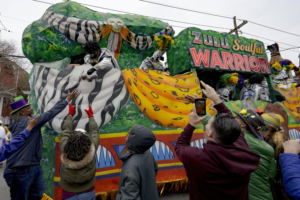 A Zulu hands the traditional coconut throws during the Krewe of Zulu Parade on Mardi Gras Day in New Orleans, Tuesday, Feb. 13, 2024. (AP Photo/Matthew Hinton)