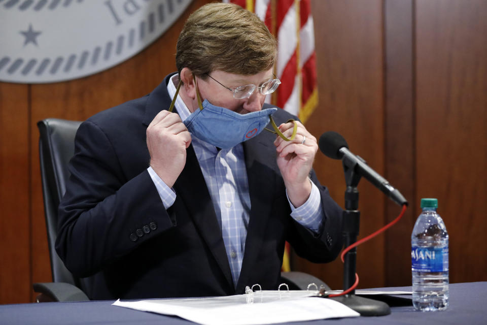 Mississippi Gov. Tate Reeves removes his face mask during a COVID-19 press briefing in Jackson, Miss., Wednesday, July 8, 2020. Reeves stressed the need for the public's personal responsibility of wearing face masks to help stem the spread of the coronavirus during the press briefing where he and others discussed the state's ongoing strategy to limit transmission. (AP Photo/Rogelio V. Solis)