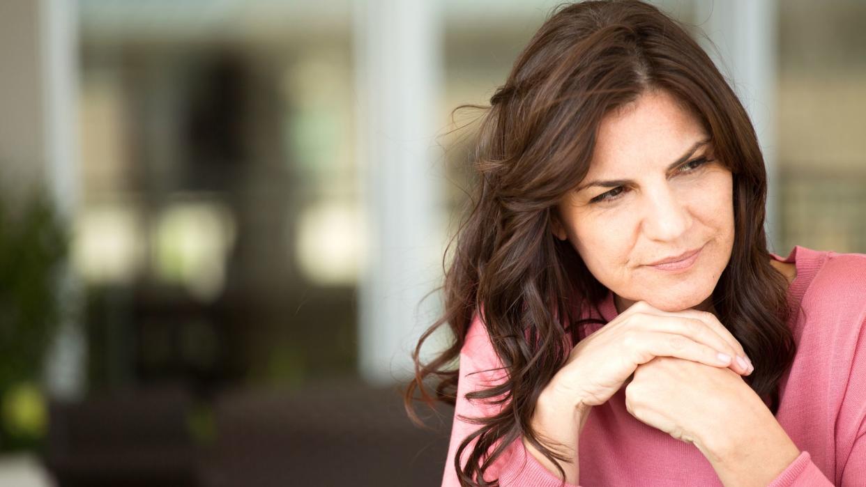 brunette woman looking serious in a pink jumper