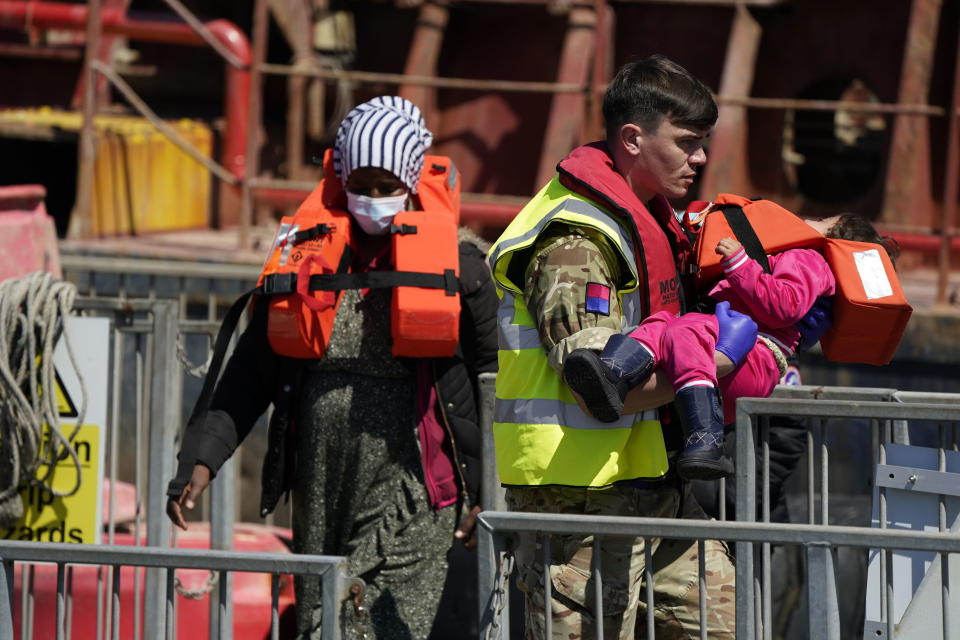 A soldier carries a child from a group of people thought to be migrants are brought in to Dover, England, by Border Force, following a small boat incident in the Channel, Tuesday June 14, 2022. (Andrew Matthews/PA via AP)