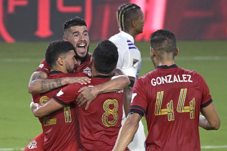 Toronto FC midfielder Jonathan Osorio (21) is congratulated by midfielder Alejandro Pozuelo, second from left, midfielder Mark Delgado (8) and defender Omar Gonzalez (44) after Osorio scored a goal during the first half of the team's MLS soccer match against Orlando City, Saturday, June 19, 2021, in Orlando, Fla. (AP Photo/Phelan M. Ebenhack)