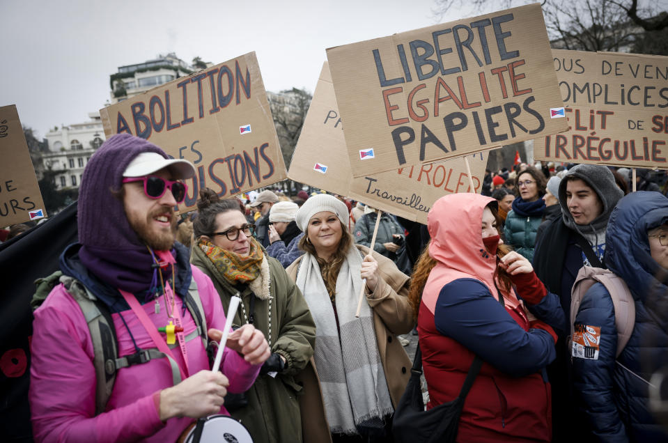An opponent of France's immigration law holds a placard that reads, "freedom, equality, papers" during a protest in Paris, Sunday, Jan. 21, 2024. The Constitutional Council is reviewing next week the government's controversial immigration law , to check that measures is in line with the Constitution. (AP Photo/Thomas Padilla)