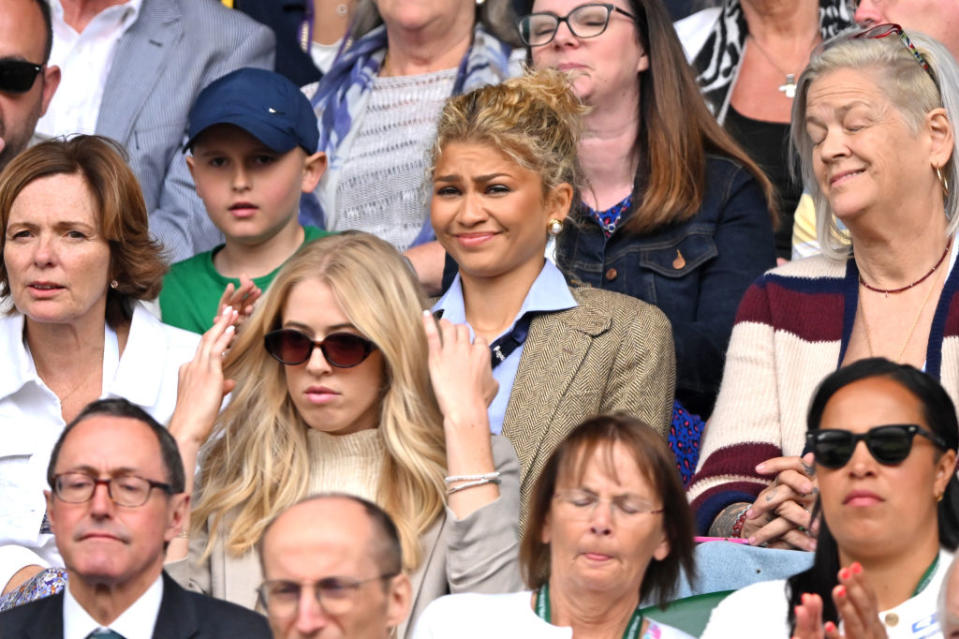 Zendaya sitting in a crowded audience, wearing a shirt with a blazer