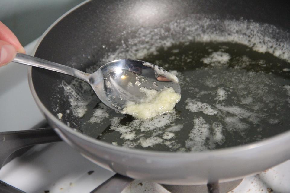 Spooning off solids from a saucepan of melted butter.