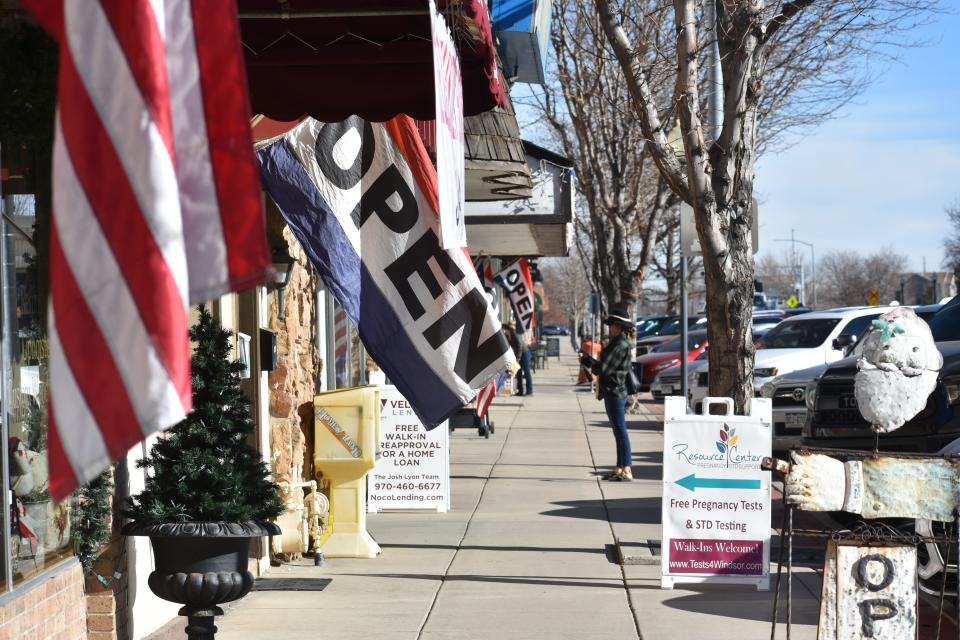 A shopper stand outside a storefront in downtown Windsor, Colo., on Dec. 1, 2021.