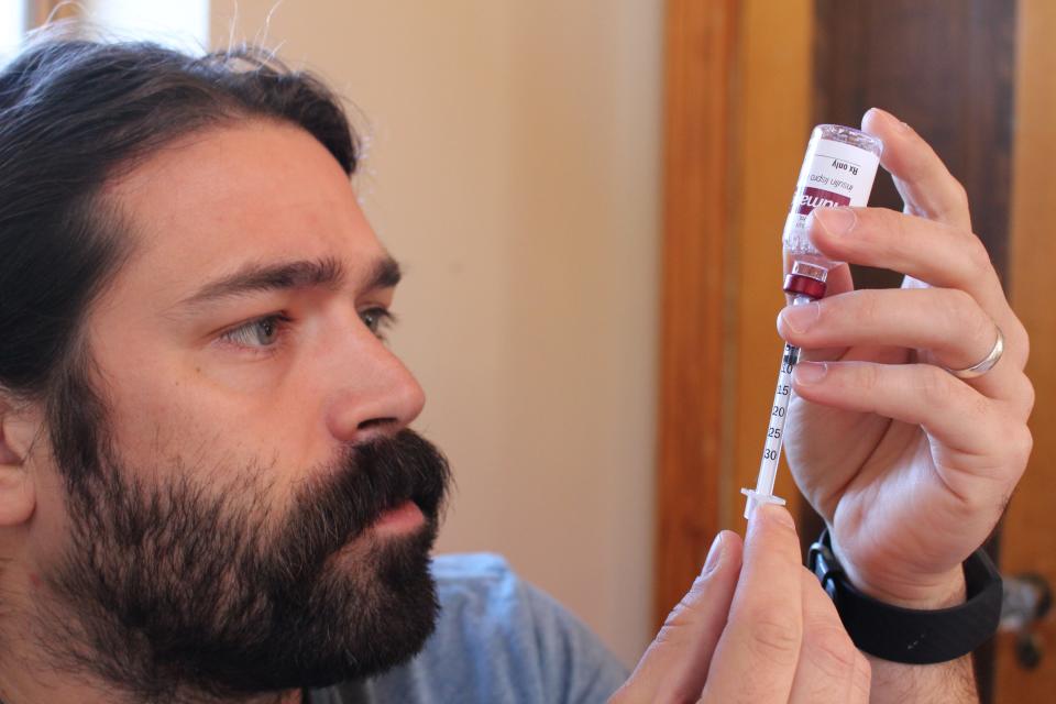 Bram Sable-Smith draws insulin into a syringe for an injection. In 10 years of living with Type 1 diabetes, Sable-Smith hadn’t had much trouble accessing the hormone that keeps him alive. Then the day before Thanksgiving, he got a voicemail from his pharmacist: His new insurance was refusing to cover the insulin that his life depends on.
