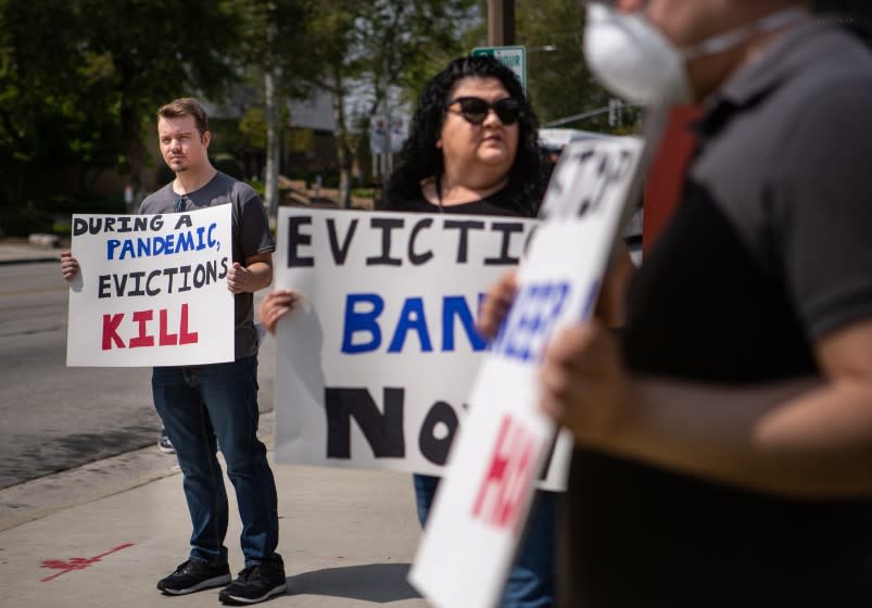 EL MONTE, CA - MARCH 29: Ian Jameson (left) of El Monte organized hold a sign along with other tenant rights activists assembled at the El Monte City Hall to demand that the El Monte City Council pass an eviction moratorium barring all evictions during the coronavirus pandemic on Sunday, March 29, 2020 in El Monte, CA. (Jason Armond / Los Angeles Times)