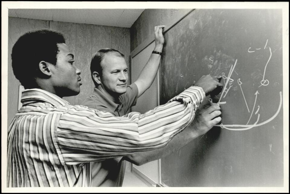 OU running back Greg Pruitt looks over X's and O's with Sooners assistant coach Barry Switzer in 1971.