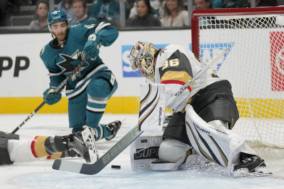 Vegas Golden Knights goaltender Logan Thompson, right, defends against a shot in front of San Jose Sharks center Luke Kunin during the first period of an NHL hockey game in San Jose, Calif., Thursday, Oct. 12, 2023. (AP Photo/Jeff Chiu)