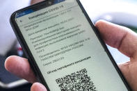 A visitor shows a COVID-19 vaccination QR code at the entrance of a restaurant in Moscow, Russia, Tuesday, June 22, 2021. As proof of vaccination for entering a restaurant, customers must visit a government website and get a QR code, a digital pattern designed to be read by a scanner. (AP Photo/Pavel Golovkin)