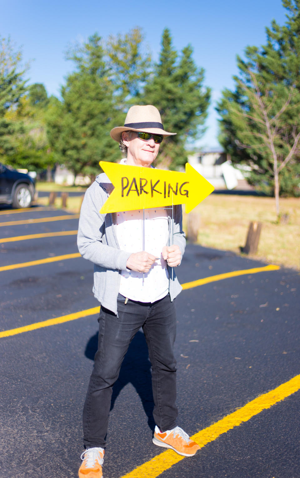 guy standing in the parking lot holding a sign that says parking