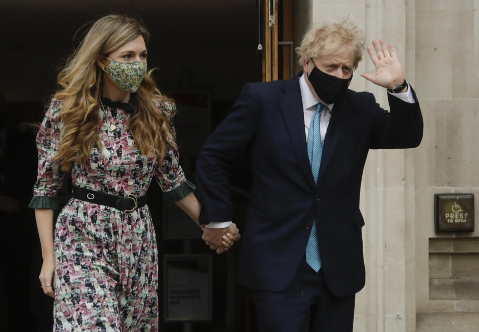 British Prime Minister Boris Johnson waves as he leaves a polling station with his partner Carrie Symonds after casting his vote in local council elections in London, Thursday May 6, 2021. Millions of people across Britain will cast a ballot on Thursday, in local elections, the biggest set of votes since the 2019 general election. A Westminster special-election is also taking place in Hartlepool, England. (AP Photo/Matt Dunham)