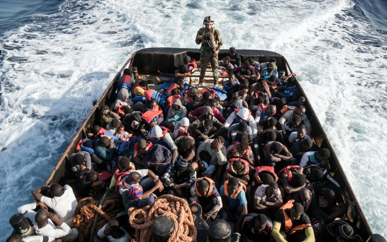 A Libyan coast guard official stands on a boat transporting rescued migrants off the country's coast in 2017