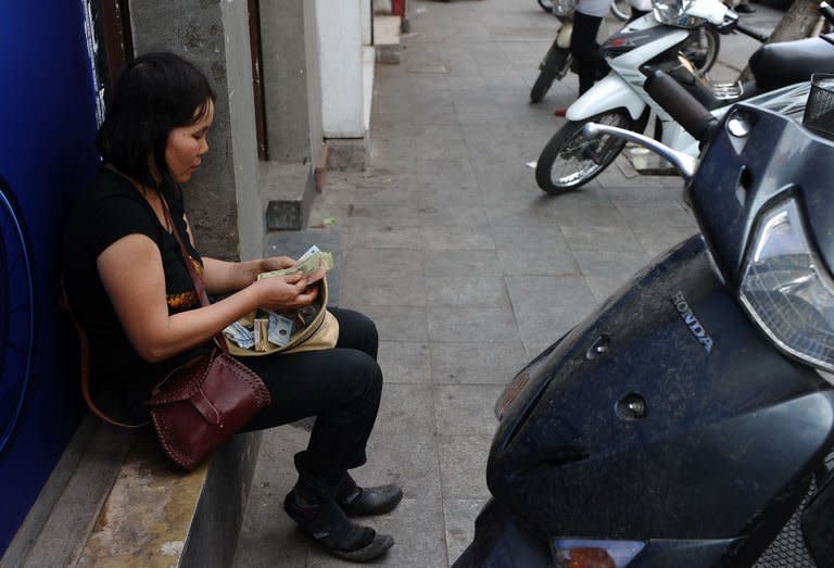 A street vendor counts banknotes on a street in downtown Hanoi, on February 7, 2013. From growing numbers of people with depression to families bankrupted by stock market investments, many are suffering in Vietnam's slow-burn economic crisis -- and blame the communist regime for their woes